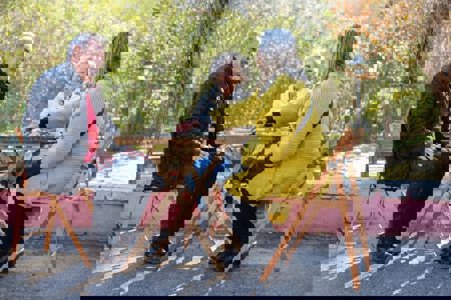 3 residents sat at a table looking happy, outside