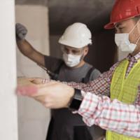 Two workmen measuring wall