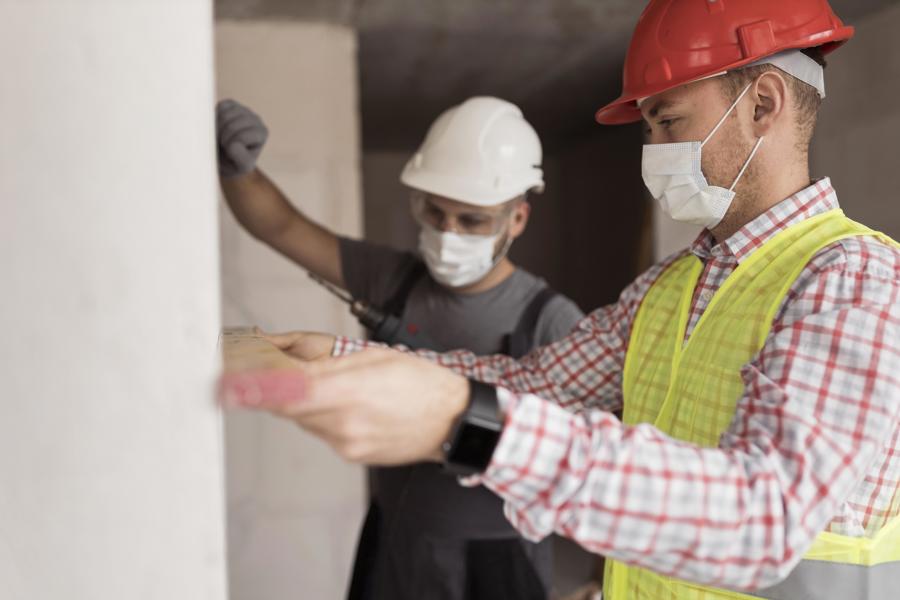 Two workmen measuring wall