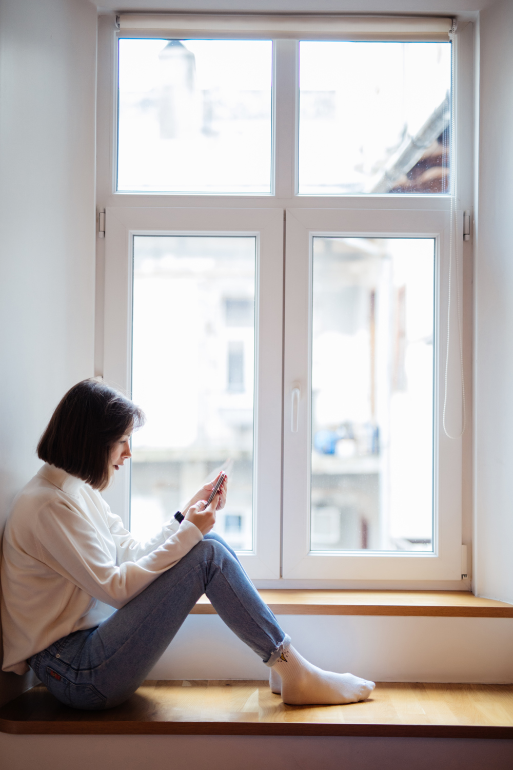 Woman on phone sitting by window